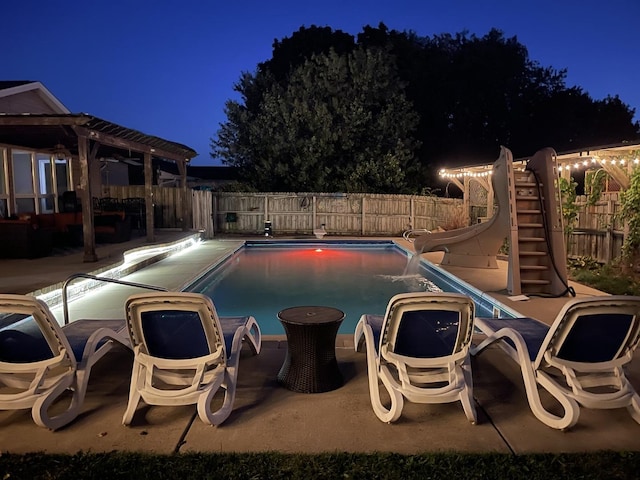 pool at twilight with a patio and a water slide