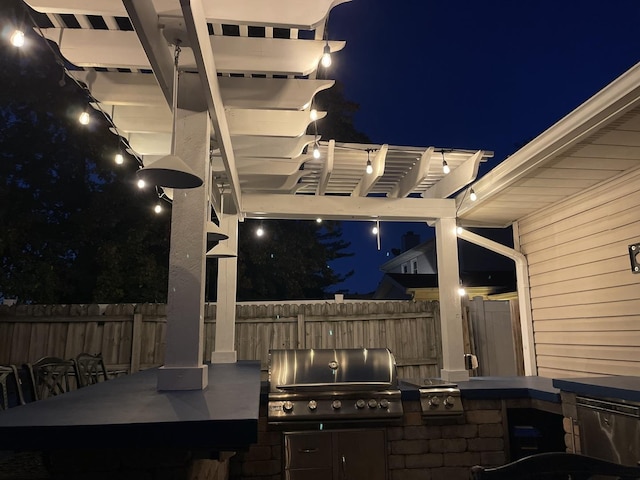 patio at twilight featuring a pergola, grilling area, and an outdoor kitchen