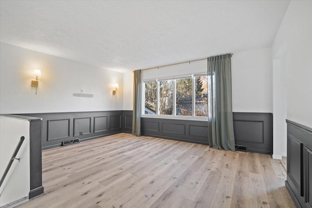 empty room with light hardwood / wood-style floors and a textured ceiling