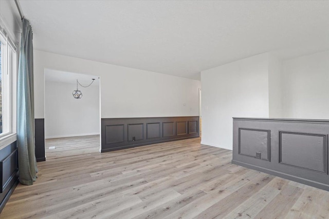 spare room with a chandelier, light hardwood / wood-style flooring, and a healthy amount of sunlight