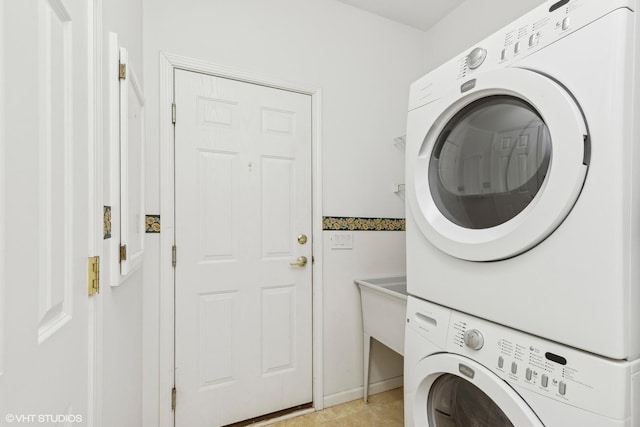 clothes washing area with light tile patterned floors and stacked washer and clothes dryer