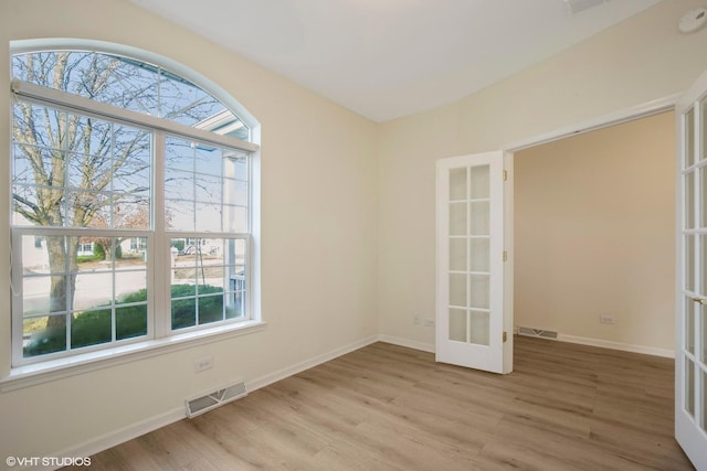 unfurnished room with french doors, light wood-type flooring, and a wealth of natural light