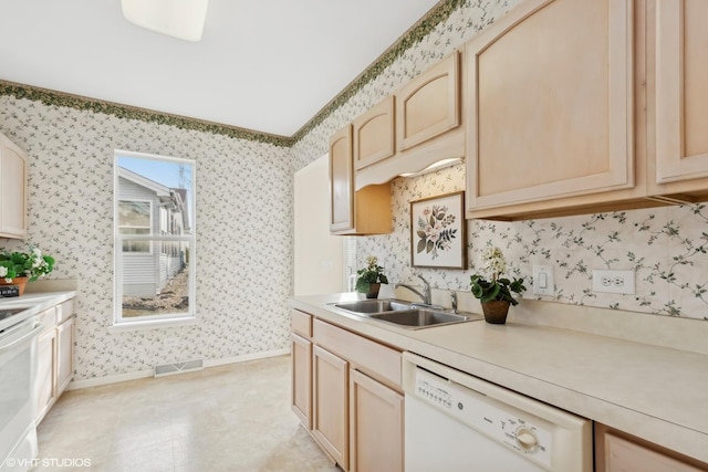 kitchen featuring white dishwasher, stove, sink, and light brown cabinetry