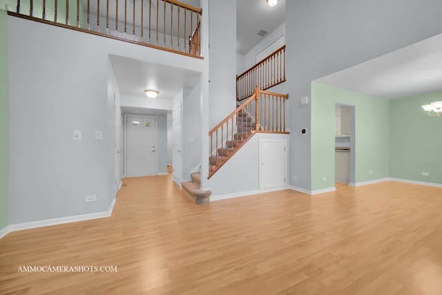 foyer entrance with light hardwood / wood-style flooring, a high ceiling, and an inviting chandelier