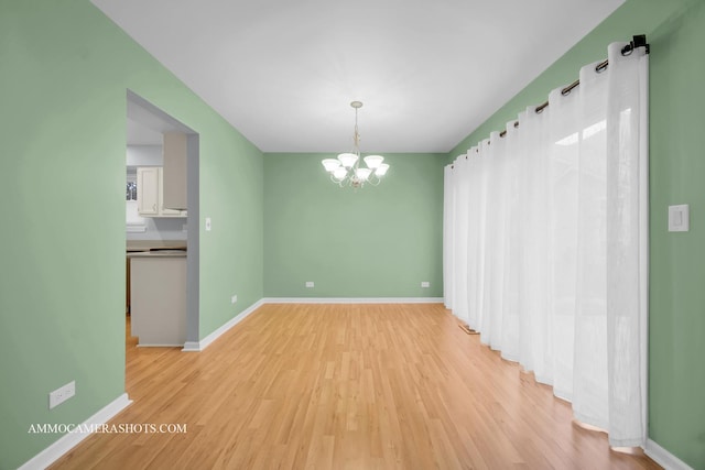 unfurnished dining area with a notable chandelier and light hardwood / wood-style flooring