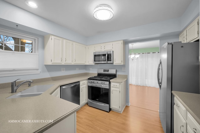 kitchen featuring white cabinetry, sink, light hardwood / wood-style flooring, a chandelier, and appliances with stainless steel finishes