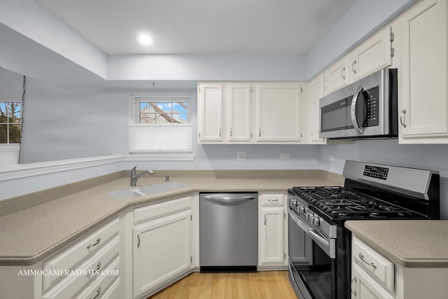 kitchen with white cabinetry, sink, appliances with stainless steel finishes, and light hardwood / wood-style flooring