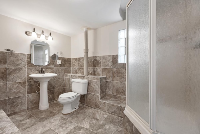 bathroom with toilet, an enclosed shower, and tile walls