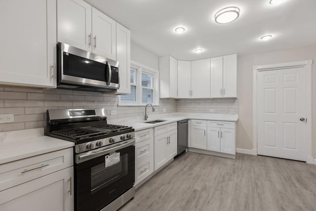 kitchen featuring white cabinetry, sink, light hardwood / wood-style floors, decorative backsplash, and appliances with stainless steel finishes