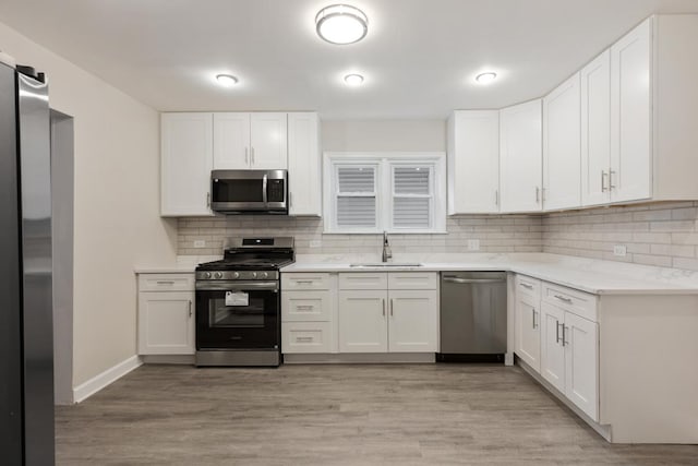 kitchen featuring sink, white cabinetry, stainless steel appliances, and light wood-type flooring