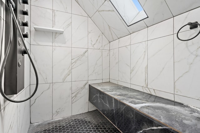 bathroom with tiled shower and a skylight