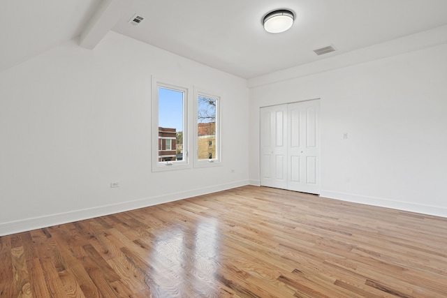 unfurnished room featuring vaulted ceiling with beams and light hardwood / wood-style floors