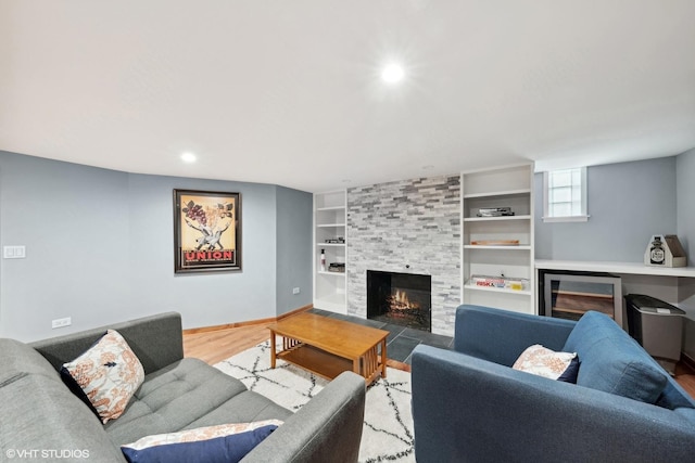 living room featuring hardwood / wood-style floors, built in shelves, and a tiled fireplace