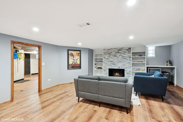 living room with light wood-type flooring and a tiled fireplace