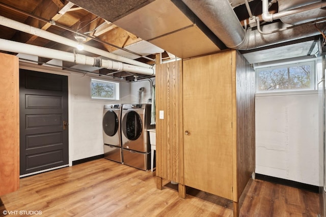 laundry room with wood-type flooring, a wealth of natural light, and washing machine and clothes dryer