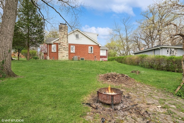 view of yard featuring central air condition unit and a fire pit