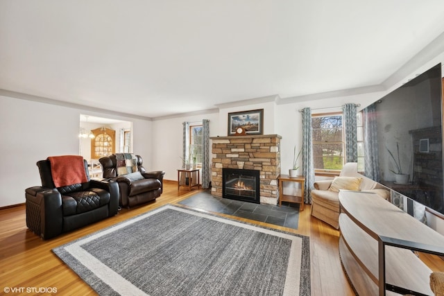 living room with hardwood / wood-style flooring, a stone fireplace, and a notable chandelier