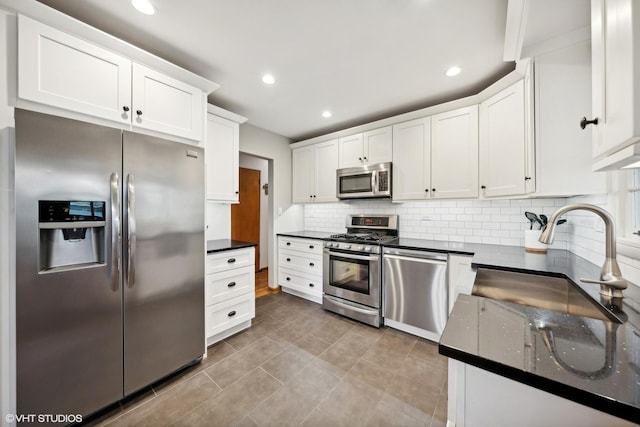 kitchen featuring sink, stainless steel appliances, light tile patterned floors, backsplash, and white cabinets