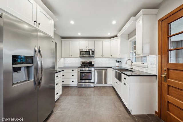 kitchen featuring appliances with stainless steel finishes, backsplash, sink, light tile patterned floors, and white cabinets