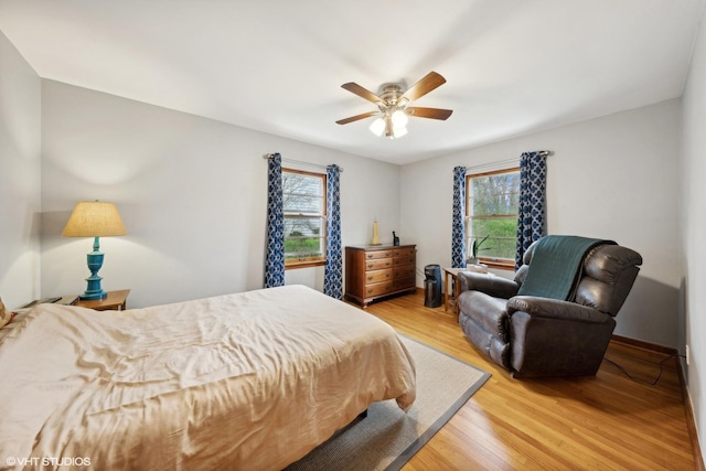 bedroom with multiple windows, hardwood / wood-style flooring, and ceiling fan