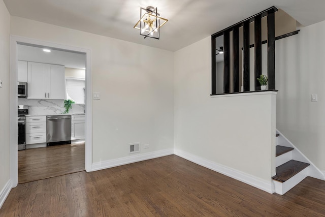 unfurnished dining area featuring a notable chandelier and dark hardwood / wood-style flooring