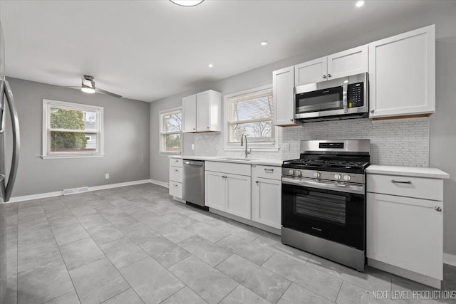 kitchen featuring ceiling fan, sink, stainless steel appliances, backsplash, and white cabinets