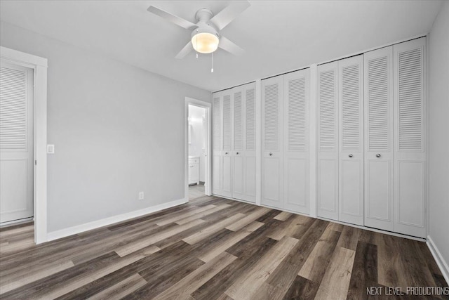 unfurnished bedroom featuring two closets, ceiling fan, and dark hardwood / wood-style floors