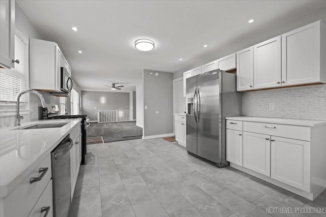 kitchen with ceiling fan, sink, stainless steel appliances, light carpet, and white cabinets