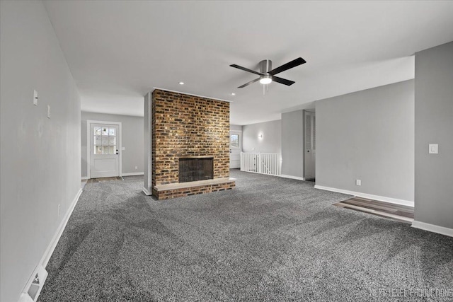 unfurnished living room featuring dark colored carpet, ceiling fan, and a fireplace