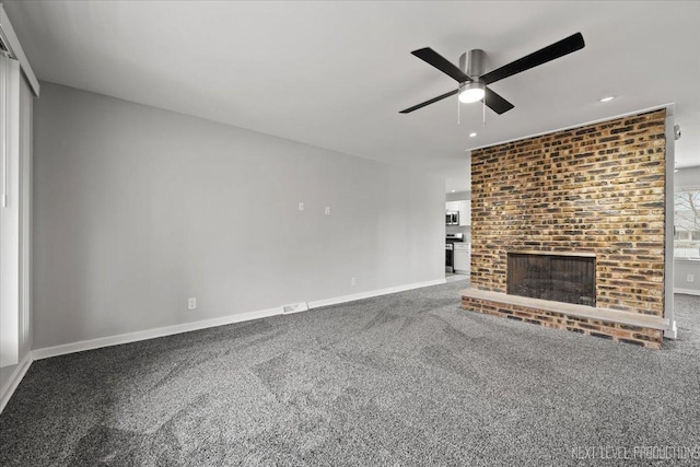 unfurnished living room with carpet, a brick fireplace, and ceiling fan