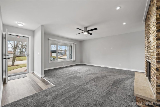 unfurnished living room featuring ceiling fan, carpet floors, a fireplace, and a wealth of natural light