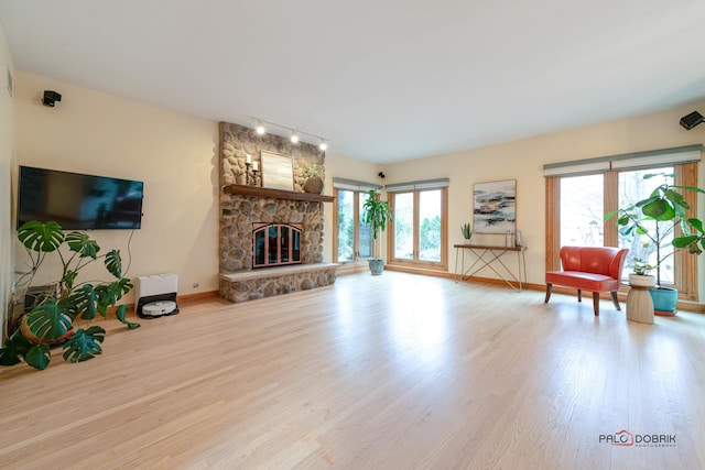 living room with a fireplace, rail lighting, and light hardwood / wood-style floors