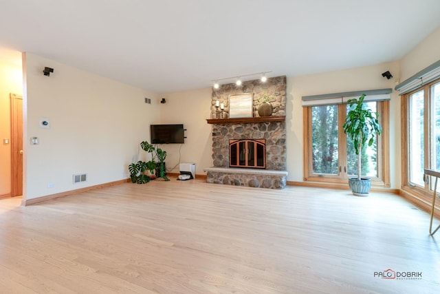 unfurnished living room featuring light wood-type flooring, a fireplace, and a wealth of natural light