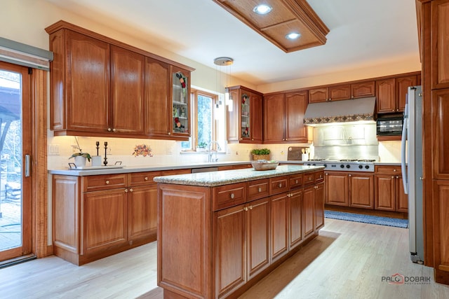 kitchen featuring appliances with stainless steel finishes, backsplash, light hardwood / wood-style floors, and a kitchen island