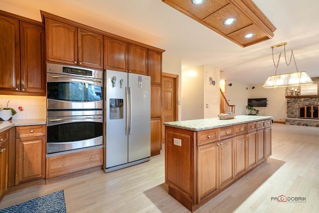 kitchen with backsplash, a fireplace, stainless steel appliances, and light hardwood / wood-style floors