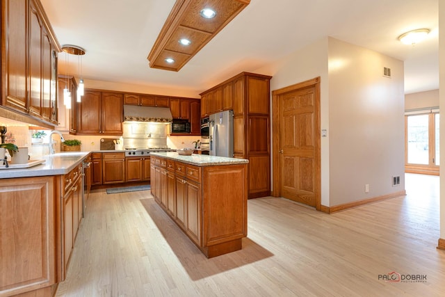 kitchen with a center island, sink, light hardwood / wood-style flooring, appliances with stainless steel finishes, and decorative light fixtures