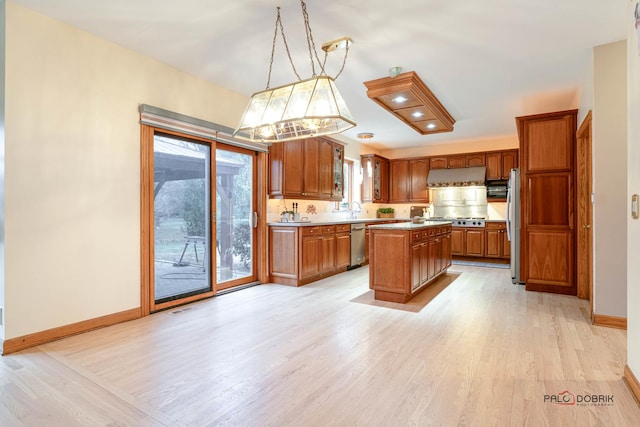 kitchen with stainless steel appliances, a kitchen island, hanging light fixtures, and plenty of natural light