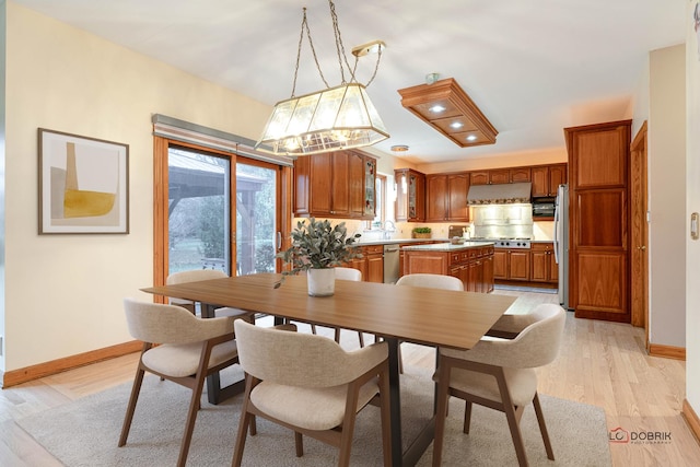 dining room featuring sink, a wealth of natural light, and light hardwood / wood-style flooring