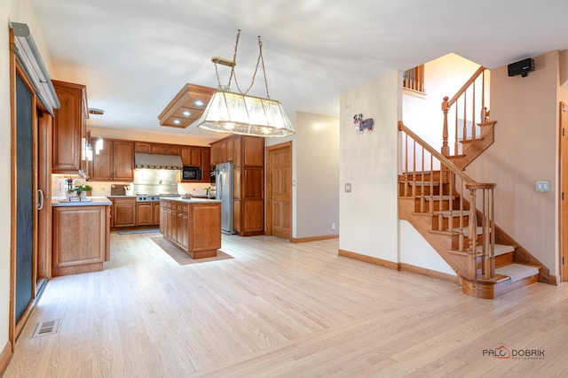 kitchen featuring pendant lighting, a center island, light hardwood / wood-style floors, and appliances with stainless steel finishes