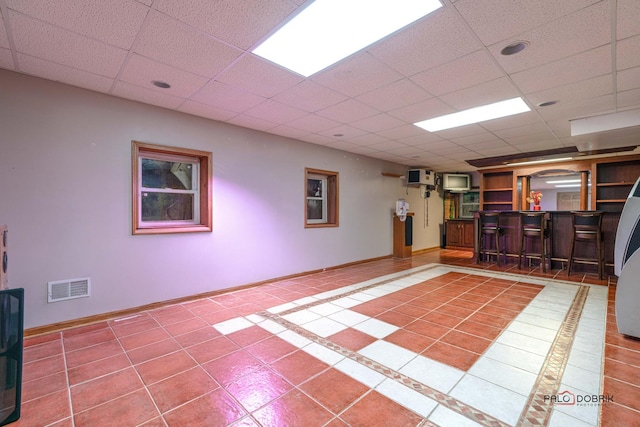 interior space with tile patterned flooring, a drop ceiling, and bar