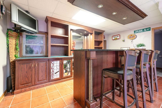 bar with a drop ceiling and light tile patterned floors