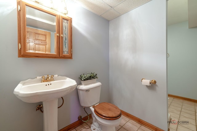 bathroom with toilet, tile patterned floors, a drop ceiling, and sink