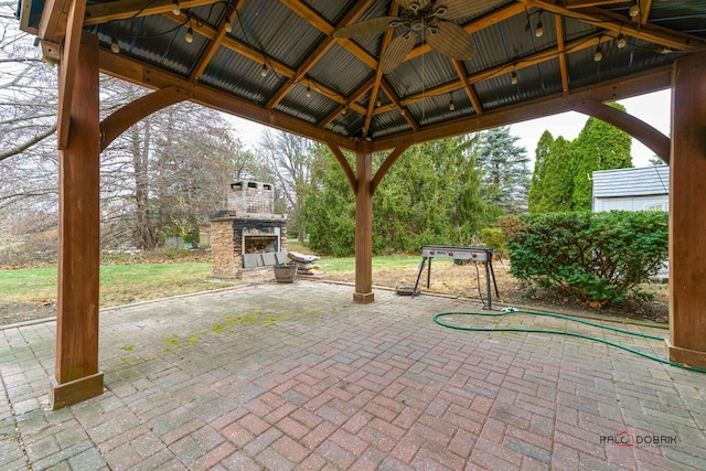 view of patio / terrace featuring an outdoor stone fireplace, ceiling fan, and a gazebo