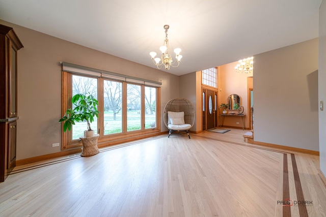 unfurnished room featuring light hardwood / wood-style floors, plenty of natural light, and a notable chandelier