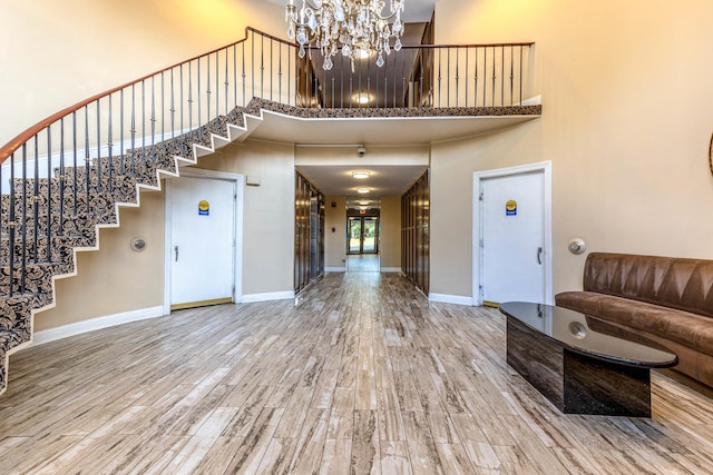 foyer with hardwood / wood-style floors, a notable chandelier, and a high ceiling