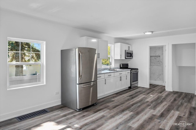 kitchen with white cabinets, appliances with stainless steel finishes, dark hardwood / wood-style floors, and sink