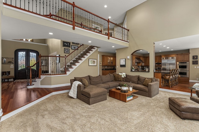 living room featuring french doors, a towering ceiling, and wood-type flooring