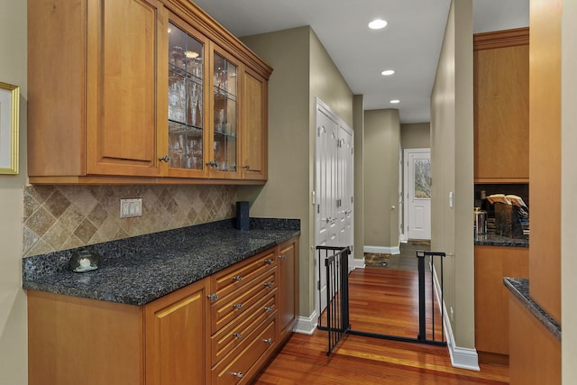 kitchen with dark stone countertops, dark hardwood / wood-style flooring, and tasteful backsplash