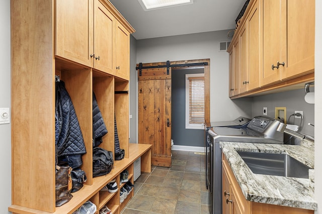 laundry room featuring cabinets, washing machine and clothes dryer, a barn door, and sink