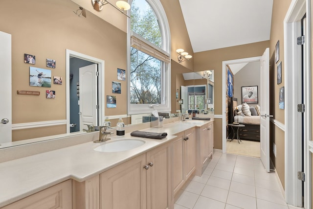 bathroom with vanity, tile patterned flooring, vaulted ceiling, and a wealth of natural light